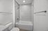 Elegant bathroom featuring a modern shower-tub combination with sleek tile backsplash and recessed lighting for a luxurious experience.