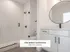 Elegant bathroom in The Select Collection at Annex West Townhomes featuring modern fixtures, sleek glass shower, and stylish round mirror.