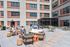 Modern apartment courtyard with stylish outdoor seating, people enjoying leisure activities, and a sleek shaded area.