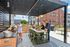 Vibrant rooftop patio with a covered dining area, featuring a group enjoying a modern outdoor kitchen setup.