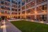 Charming courtyard with ambient string lights, modern seating, and lush green lawn at dusk.