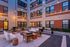 Chic urban courtyard with ambient string lights, modern seating, and a cozy fire pit, perfect for evening relaxation.