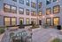 Charming apartment courtyard featuring string lights, modern seating, and lush planters for a cozy outdoor gathering space.
