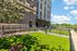 Charming apartment building with modern architecture, complemented by lush green landscaping and a sunny outdoor space.