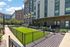 Charming apartment exterior with modern architecture, lush green lawn, and inviting pathways in a vibrant community setting.