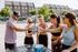 Group of friends enjoying a sunny outdoor gathering, toasting with drinks by a sand volleyball court, showcasing a vibrant community lifestyle.