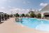 Inviting outdoor pool area at a modern apartment complex, featuring stylish cabanas and sun loungers for relaxation.