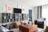 1810 The Social, interior, living room, black, tan, blue and red decor, sofas, arm chairs, sofa, books on shelves, tv