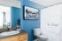 1810 The Social, interior, bathroom, blue and white decor, 'The Social' Logo on the shower curtain, wood cabinets, large mirror, blue wall, white toilet, white sink