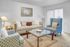 Inviting living room with elegant beige sofa, patterned armchairs, and glass coffee table, exuding comfort and style. | Wingpointe | Apartments in Clearfield, Utah