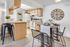 Bright kitchen with modern amenities, featuring wooden cabinets, a central island with seating, and contemporary decor.