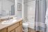 Bright and modern bathroom featuring a sleek countertop, elegant faucet, and stylish shower curtain.