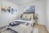 Inviting bedroom with stylish decor, featuring a comfortable bed, modern art, and natural light.