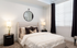Sophisticated bedroom with cozy bed, plush pillows, stylish round mirror, and warm lighting. | Point of View | Apartments in Draper, Utah