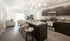Luxurious kitchen island with granite countertops and modern living room in open-concept apartment. | Point of View | Apartments in Draper, Utah