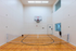 Versatile indoor court with gleaming hardwood floor, equipped for basketball and badminton in a bright, spacious facility.