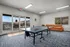 Bright recreation room with a ping pong table, cozy orange sofa, and stunning outdoor views through large windows.