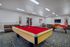 Inviting recreation room with a vibrant red pool table, cozy seating area, and modern decor, perfect for entertainment and relaxation.