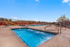 Inviting outdoor pool area with sun loungers and vibrant landscaping, offering the perfect space for relaxation and leisure under a clear blue sky.