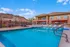 Inviting outdoor pool area with lounge chairs, surrounded by scenic desert hills and modern apartment architecture.