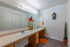 Modern bathroom with double sinks, artistic flower vases, and stylish orange accents, offering a chic and serene ambiance.