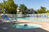 Inviting outdoor pool area with comfortable lounge chairs, vibrant umbrellas, and a relaxing jacuzzi in a serene residential setting. | Wingpointe | Apartments in Clearfield, Utah