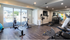Modern fitness room with state-of-the-art exercise equipment, large windows overlooking a serene outdoor pool area. | Wingpointe | Apartments in Clearfield, Utah