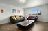 Bright and inviting living room with modern leather sofas, vibrant decor, and a large window offering scenic views.