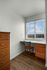 Cozy office nook with a wooden desk and chair, featuring a bright window view, perfect for work-from-home comfort.