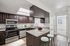 Modern kitchen with elegant dark wood cabinets, sleek granite countertops, and stainless steel appliances, featuring a breakfast bar with stylish stools. | Windmill Cove | Apartments in Sandy, Utah