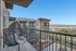 Modern balcony with an egg-shaped wicker chair offering breathtaking views of a cityscape and distant mountains, perfect for relaxation. | Point of View | Apartments in Draper, Utah