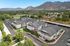 Aerial view of charming apartment complex surrounded by lush greenery and scenic mountains, offering a picturesque and tranquil residential setting.