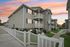 Charming apartment complex exterior featuring modern architecture, stone accents, and inviting balconies under a picturesque sunset sky.