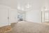 Bright and inviting living room with plush carpet, modern light fixtures, and sliding glass doors opening to a balcony.