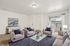 Chic living room with plush beige seating, elegant artwork, and a glass coffee table, opening to a bright balcony view.