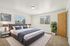 Bright, modern bedroom with luxurious king-size bed, stylish decor, and ample natural light from large windows.