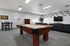 Inviting entertainment room with a stylish pool table, sleek black sofas, and a modern wall-mounted TV, perfect for relaxation and socialization.
