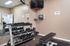 Modern fitness corner with a sleek dumbbell rack, comfortable bench, and wall-mounted TV for an enhanced workout experience.