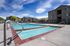 Bright and inviting outdoor pool area with clean waters, surrounded by modern apartment buildings and scenic views.