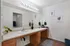 Elegant bathroom featuring a large mirror, double sinks, and chic wooden cabinetry accented by lush greenery and stylish decor.