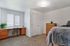 Bright and cozy bedroom with a plush carpet, elegant desk space, and ample natural light from the window. Featuring warm wooden furniture and a comfortable bed for a serene atmosphere.