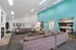 Inviting open-plan living area with vibrant teal accent wall, contemporary sofas, and a cozy fireplace leading into a modern kitchen.