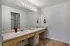 Spacious bathroom with dual sinks, large mirror, and elegant lighting, offering ample cabinetry and modern fixtures.