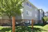 Charming apartment exterior with lush green lawn, mature trees, and relaxing hammocks, perfect for outdoor leisure.