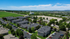 Aerial view of a vibrant apartment complex surrounded by lush greenery, with ample parking space and scenic countryside views.