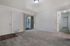 Bright and inviting living room with plush carpeting, sliding glass door to a serene balcony view, and inviting hallway access.