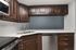 Elegant modern kitchen with rich wood cabinets, sleek stainless steel appliances, and a stylish L-shaped countertop design.