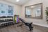 Bright and modern home gym with sleek hardwood floors, a full wall mirror, and a versatile selection of free weights and yoga mats.