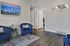 Inviting living room at Triton Heights featuring elegant blue armchairs, a stylish area rug, and modern wall art, creating a cozy and contemporary atmosphere.