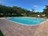 Inviting outdoor pool area surrounded by lush greenery, featuring cozy lounge chairs and a serene blue sky backdrop.